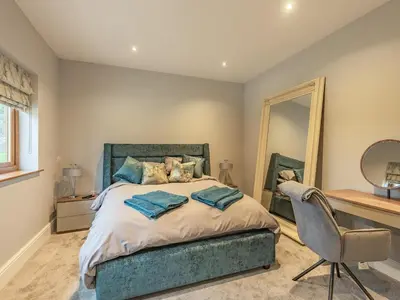 a bedroom with a bed with a chair and a mirror at Hoole Summer House in Elswick