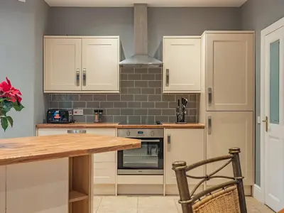 a kitchen with white cabinets and a wooden table at Hoole Summer House in Elswick