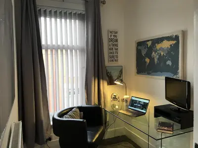 a living room with a chair and a desk with a laptop at Bright Spacious 3-bed with office & patio, Preston in Preston