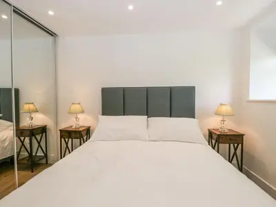 a bedroom with a large white bed and two lamps at Bank Hurst Coach House in Ulverston