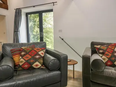 a living room with two leather couches and a table at Bank Hurst Coach House in Ulverston