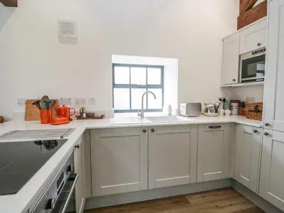 a kitchen with white cabinets and a sink at Bank Hurst Coach House in Ulverston
