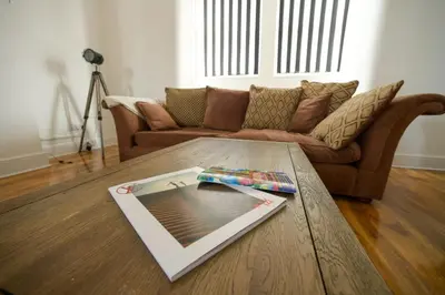 a book on a table in a living room with a couch at HOT TUB JACUZZI on private terrace FREE GATED PARKING sleeps 8 in Blackpool