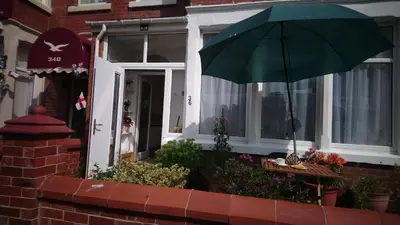 a green umbrella in front of a house at Renovated 4-Bed Home Sleeps 9 with Parking & Spa in Blackpool