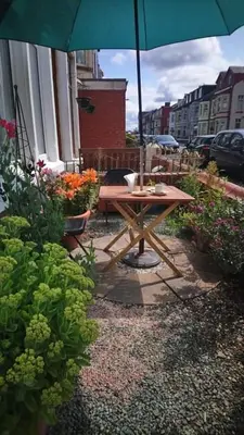 a picnic table with an umbrella in a garden at Renovated 4-Bed Home Sleeps 9 with Parking & Spa in Blackpool