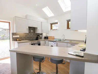 a kitchen with white cabinets and a wooden counter top at Little Barn in Grange Over Sands