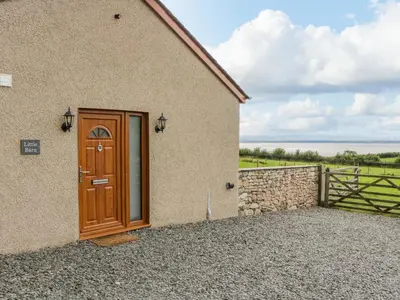 a building with a wooden door and a fence at Little Barn in Grange Over Sands
