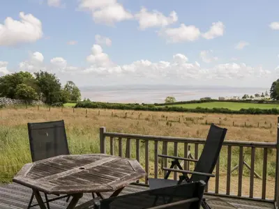 a table and chairs on a deck with a view of the ocean at Little Barn in Grange Over Sands