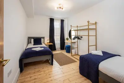 a bedroom with two beds and a wooden floor at Blueberries Apartments by Sasco in Blackpool