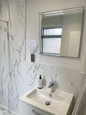 a white bathroom with a sink and a mirror at Smith Stayz Apartments in Blackpool