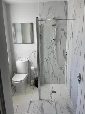 a white bathroom with a toilet and a shower at Smith Stayz Apartments in Blackpool