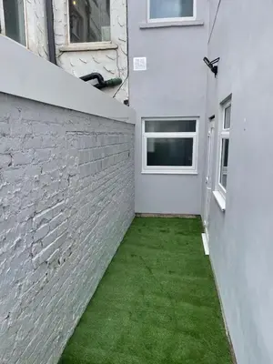 a courtyard with green grass next to a brick wall at Smith Stayz Apartments in Blackpool