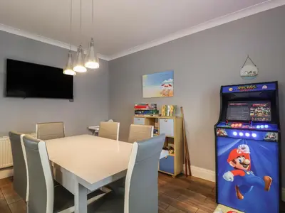 a dining room with a table and a pinball machine at 71 Nutter Road in Cleveleys