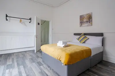 a bedroom with a bed with a yellow blanket on it at Huge 7 Bed Home For Groups in Liverpool