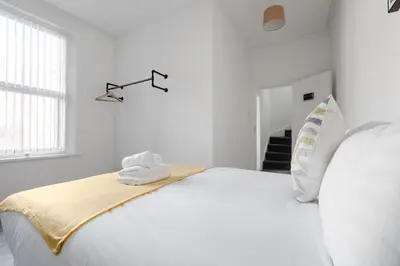 a white bedroom with a large white bed and a window at Huge 7 Bed Home For Groups in Liverpool