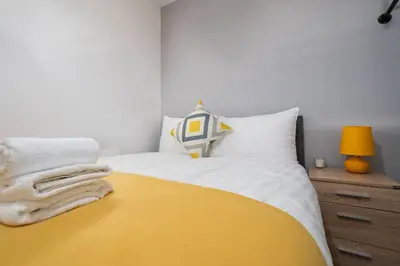 a bedroom with a yellow and white bed and a lamp at Huge 7 Bed Home For Groups in Liverpool