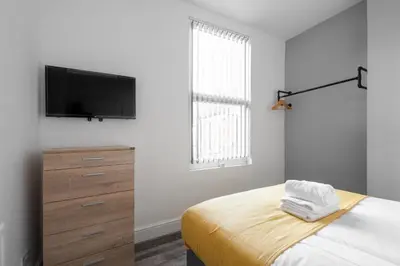a bedroom with a bed and a flat screen tv at Huge 7 Bed Home For Groups in Liverpool