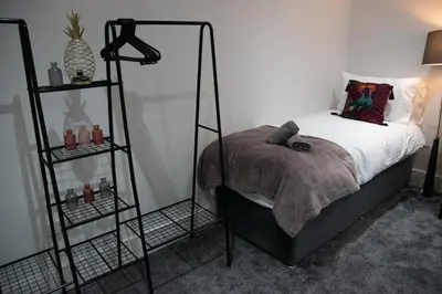 a bedroom with a bed with two shelves next to it at Ideal Lodgings in Accrington in Accrington