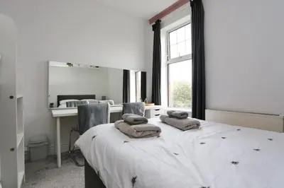 a bedroom with a large bed with two towels on it at The Hot Tub Townhouse by Holiday Heim in Lytham St Annes