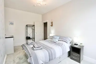 a white bedroom with a bed with towels on it at The Hot Tub Townhouse by Holiday Heim in Lytham St Annes