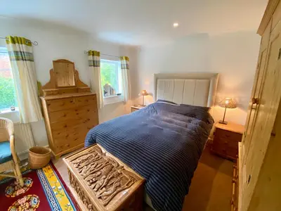 a bedroom with a bed and a dresser and windows at Spacious Two Bedroom House - TM in Southport