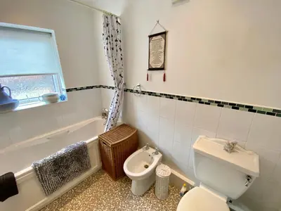 a bathroom with a toilet and a bath tub at Spacious Two Bedroom House - TM in Southport