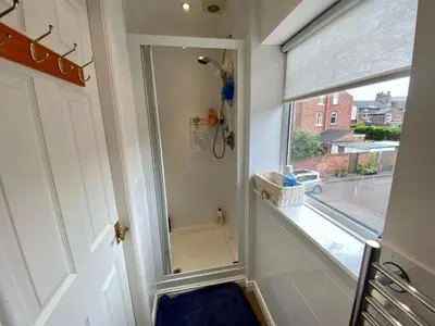 a bathroom with a shower with a mirror next to a window at Spacious Two Bedroom House - TM in Southport