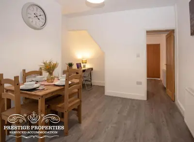 a dining room with a table and a clock on the wall at Cross Street by Prestige Properties SA in Barrow in Furness