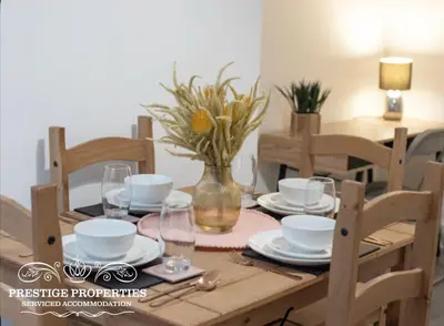 a wooden table with plates and a vase with flowers at Cross Street by Prestige Properties SA in Barrow in Furness