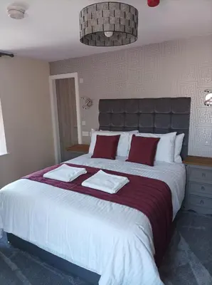 a bedroom with a large bed with red and white pillows at Rose James Apartments in Blackpool