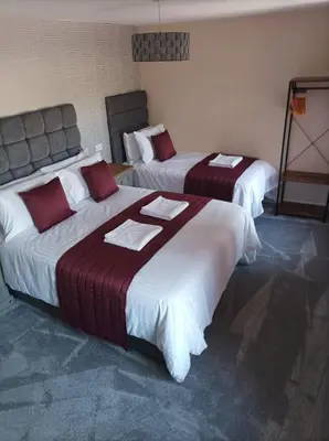 a hotel room with two beds with red and white sheets at Rose James Apartments in Blackpool