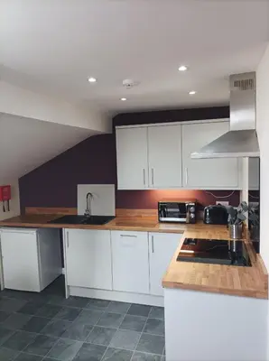 a kitchen with white cabinets and a sink at Rose James Apartments in Blackpool
