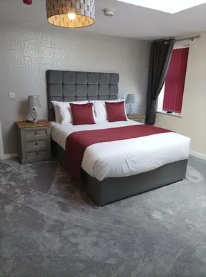 a bedroom with a large bed with red pillows at Rose James Apartments in Blackpool