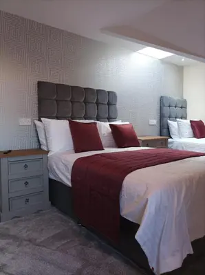 a bedroom with two beds with red and white pillows at Rose James Apartments in Blackpool