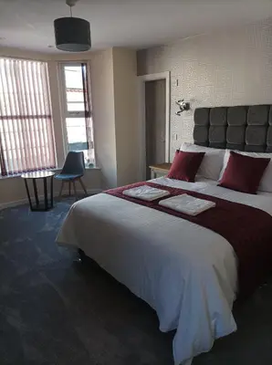 a bedroom with a large bed with red pillows at Rose James Apartments in Blackpool