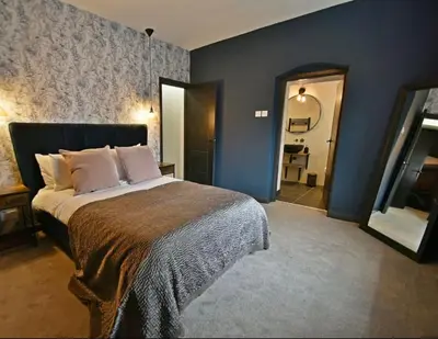 a bedroom with a large bed and a bathroom at Boutique cottage set in historic town of Clitheroe in Clitheroe