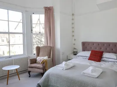 a bedroom with a bed and a chair and a window at 112 Balmoral Road in Morecambe