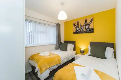 two beds in a room with yellow walls at warm modern 3 bedroom house free secure off road parking, wifi & sky sleep upto 6 guest 2 bathrooms in Aintree