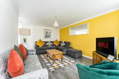 a living room with a couch and a tv at warm modern 3 bedroom house free secure off road parking, wifi & sky sleep upto 6 guest 2 bathrooms in Aintree