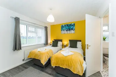 two beds in a room with yellow walls at warm modern 3 bedroom house free secure off road parking, wifi & sky sleep upto 6 guest 2 bathrooms in Aintree
