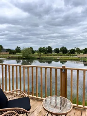 a view of a lake from a deck with a table and chairs at Edmonton Lodge in Clitheroe