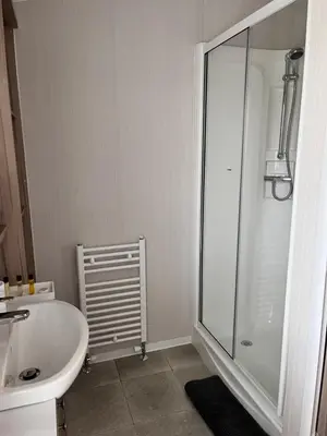 a white bathroom with a shower and a sink at Edmonton Lodge in Clitheroe