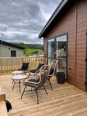 a wooden deck with chairs and a table on it at Edmonton Lodge in Clitheroe