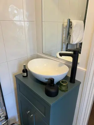 a bathroom with a white sink on a blue cabinet at Church Mouse Cottage Clitheroe in Clitheroe