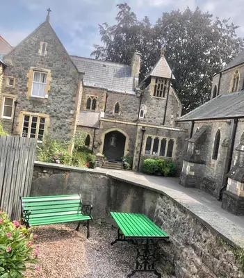 a green bench sitting in front of a castle at Church Mouse Cottage Clitheroe in Clitheroe