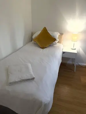 a white bed with a yellow pillow and a side table at Princess Gardens Liverpool Accessible - Infinity in Liverpool