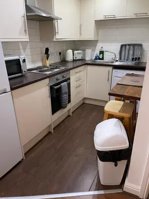 a kitchen with white cabinets and a wooden floor at Modern, Quiet, Sleeps 10, Anfield, Tourists, Liverpool in Liverpool