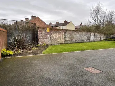 a brick wall next to a street with a yard at Modern, Quiet, Sleeps 10, Anfield, Tourists, Liverpool in Liverpool