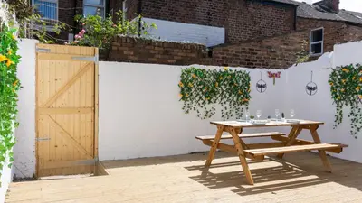 a wooden picnic table next to a fence with flowers at Coningsby House - Air Host & Stay - 6BR, Sleeps 14 in Liverpool
