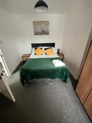 a bedroom with a bed with a green blanket at Lovely refurbished apartments, Morecambe Promenade in Morecambe